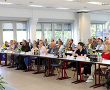 Blick auf den gut besuchten Tagungsraum mit Reihen von Teilnehmenden an Tischen.