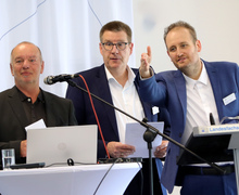 Drei Männer am Rednerpult.