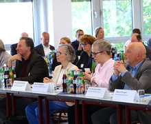 Frontale Perspektive auf den Saal mit voll besetzten Tischen und aufmerksamem Publikum.