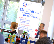Teilnehmendengruppe vor einem Roll-up mit dem Schriftzug „Qualität in der Hessischen Weiterbildung“. 
